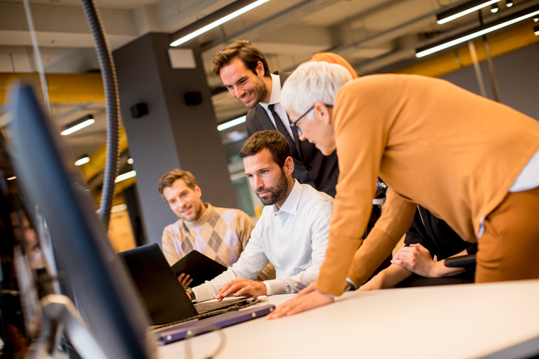 Equipe reunida em torno de computador.